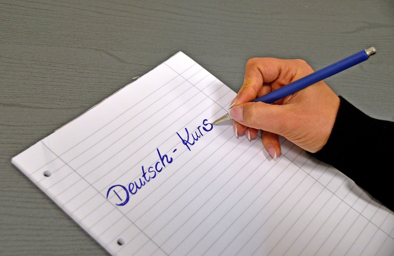 A hand writing the German words for German course in a notebook