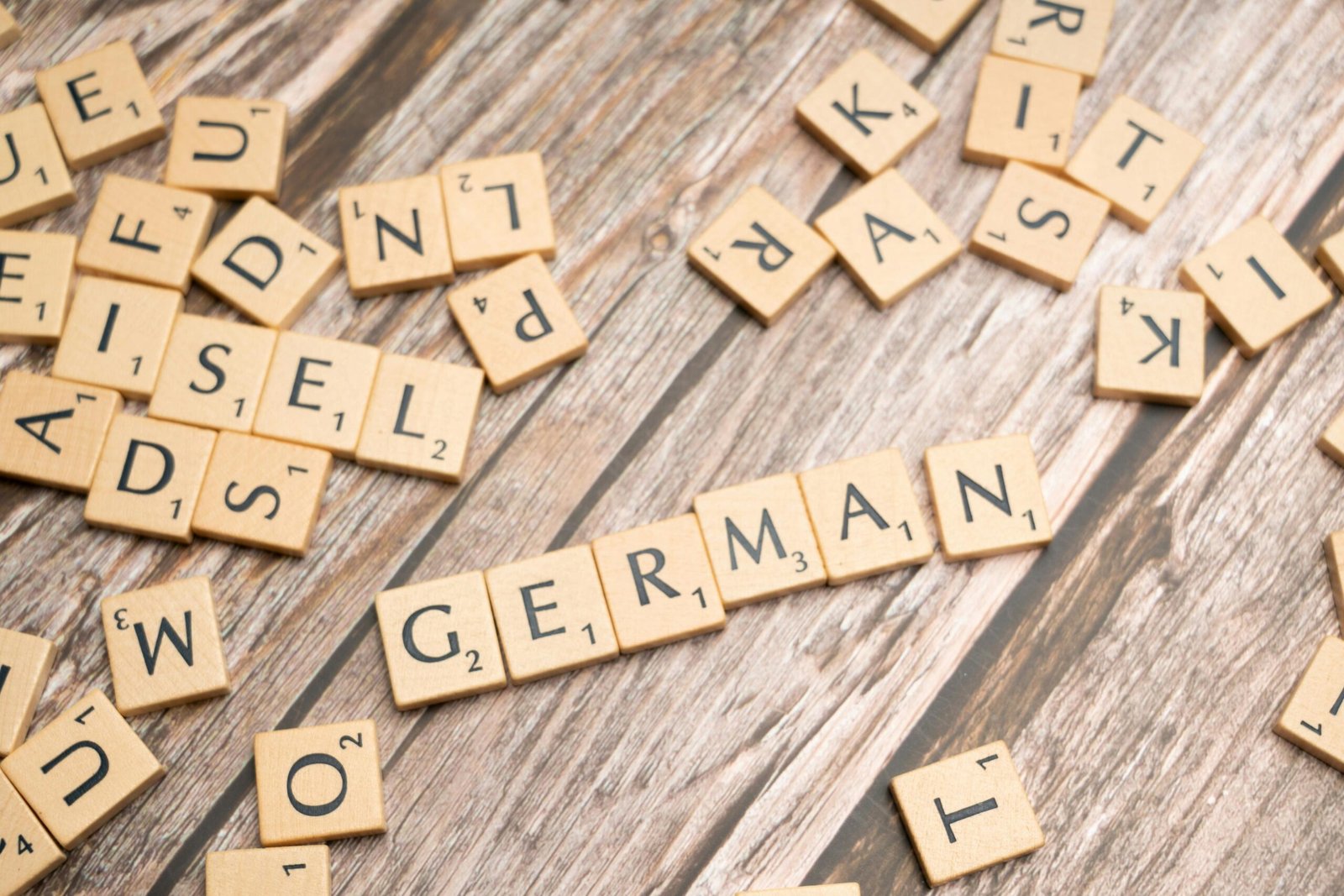 Wooden letter tiles on a table spelling out 'German'. Perfect for language, culture, or typography themes.